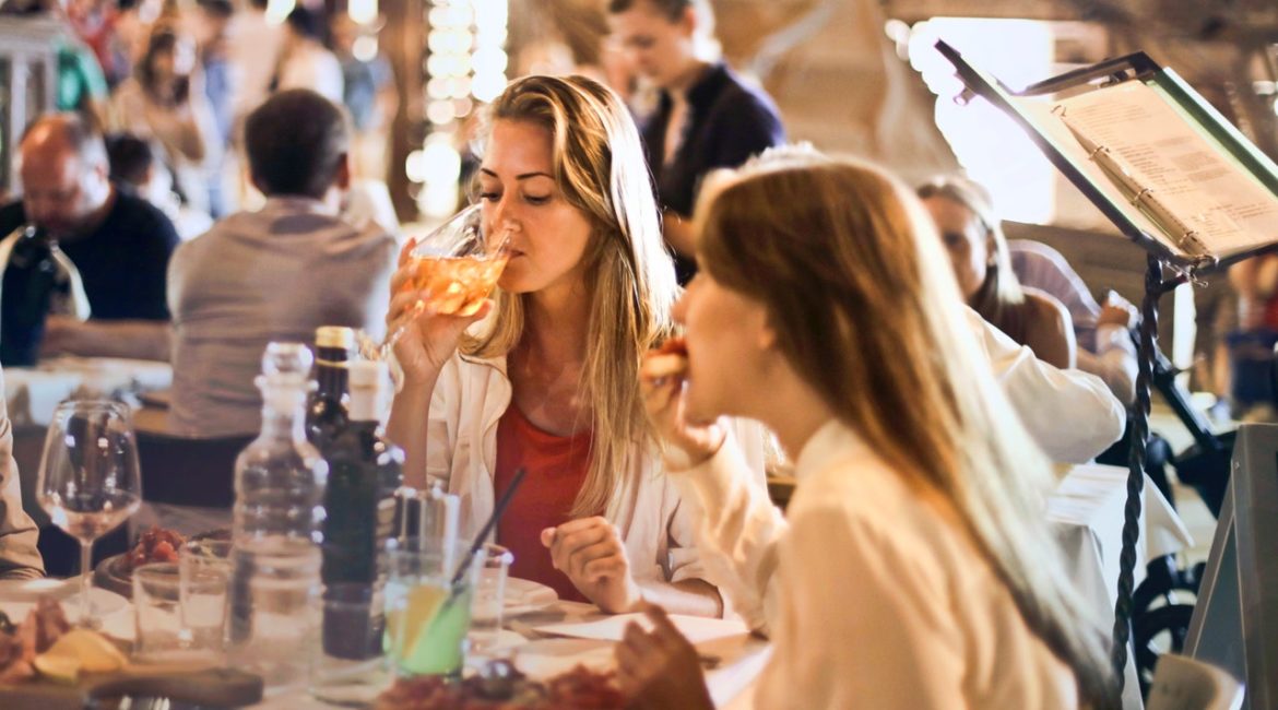 Damer der drikker vin på restaurant