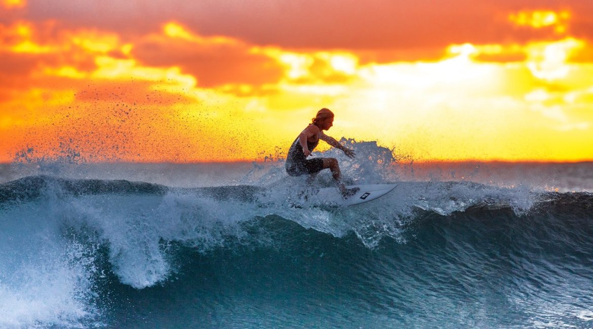 Mand surfer i solnedgang på hawaii